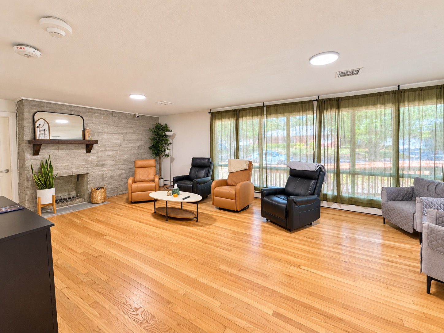 Wide view of the living room with recliners, fireplace, and windows